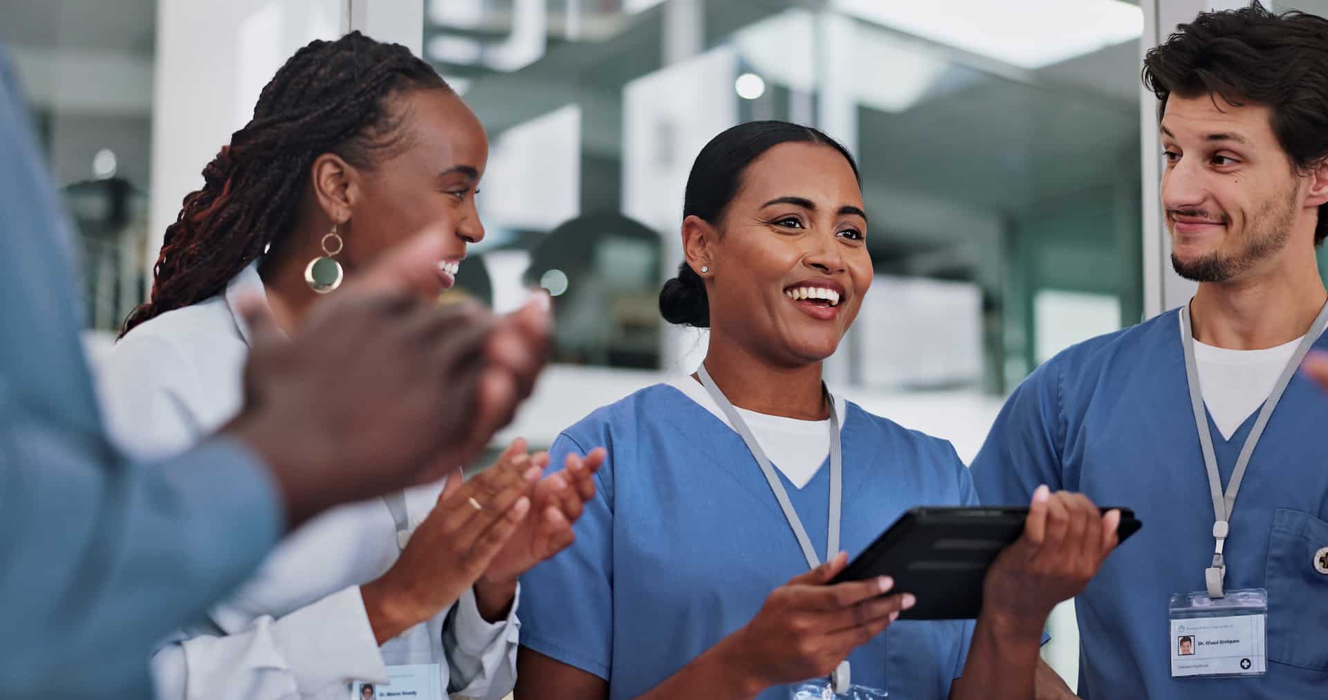 Group of nurses standing together in a hospital and clapping.